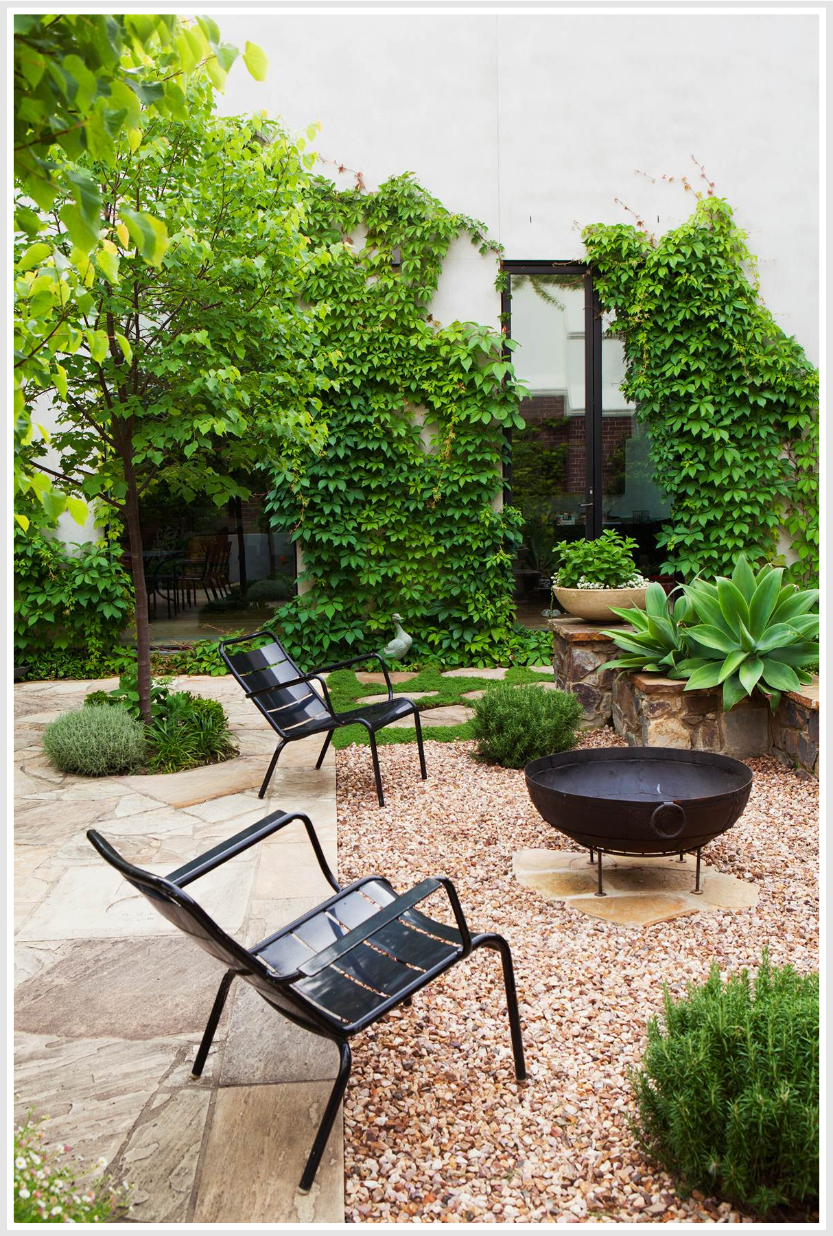 Outdoor firepit next to patio, 2 metal chairs around it.