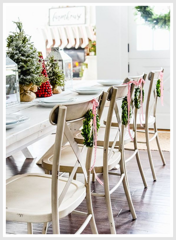 Row of dining chairs with wreaths hanged on them.