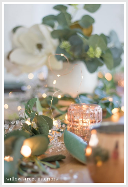 Fairy lights in a jar on a table with plants.