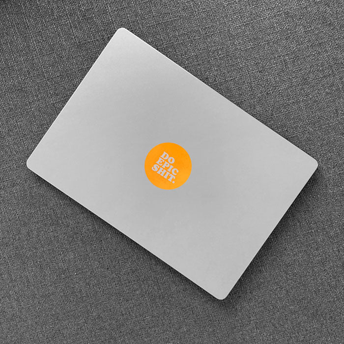 neon orange "get shit done" apple sticker on a macbook