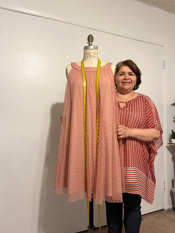 Edelmira wearing a red shirt holding a peach-colored dress