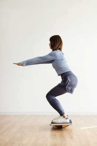 a woman squatting on a balance board
