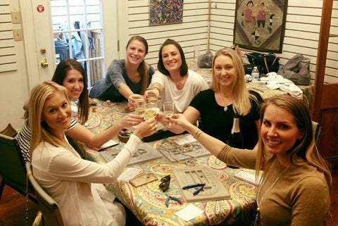 Girls night Moms night out at the bead shop ladies toast with wine before they begin beading