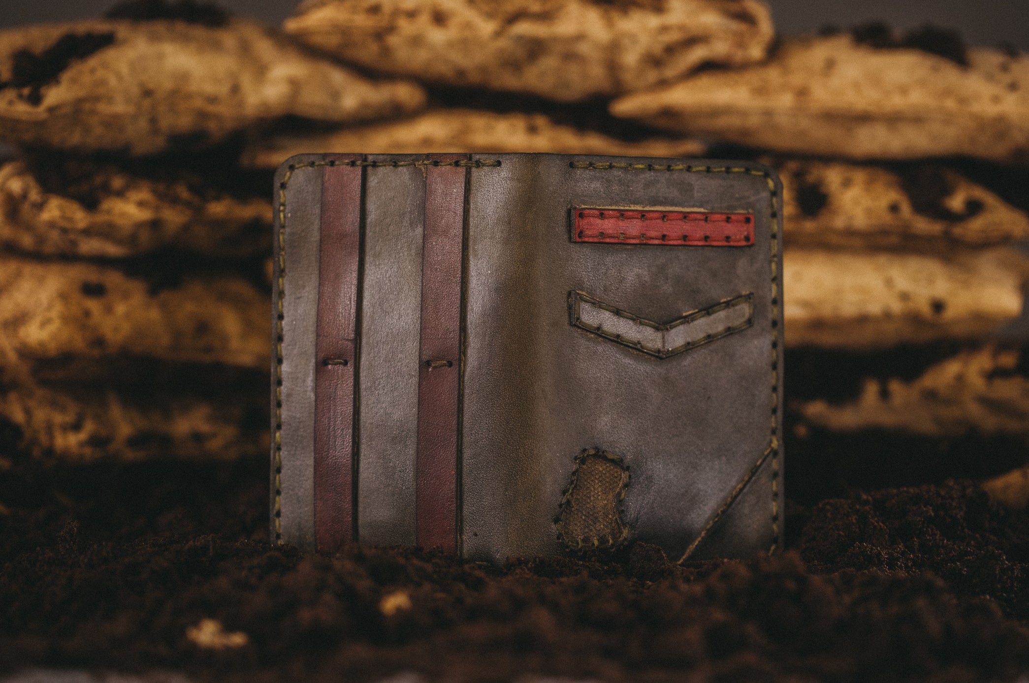 A military themed wallet stands in dirt with sand bags in background