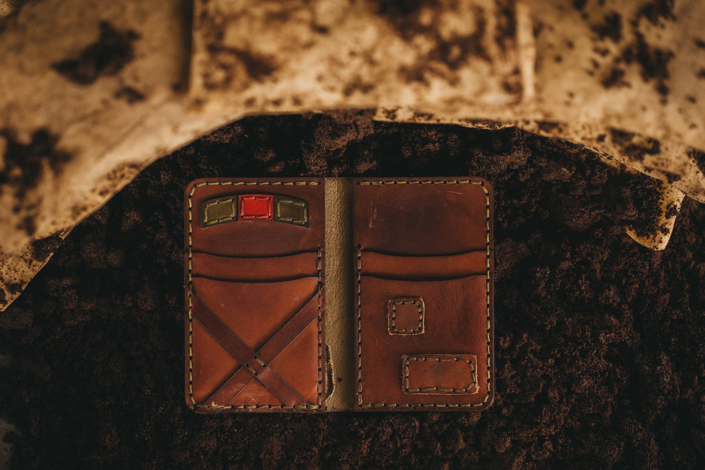 A military theme wallets sits on top of dirt with sand backs surrounding it.
