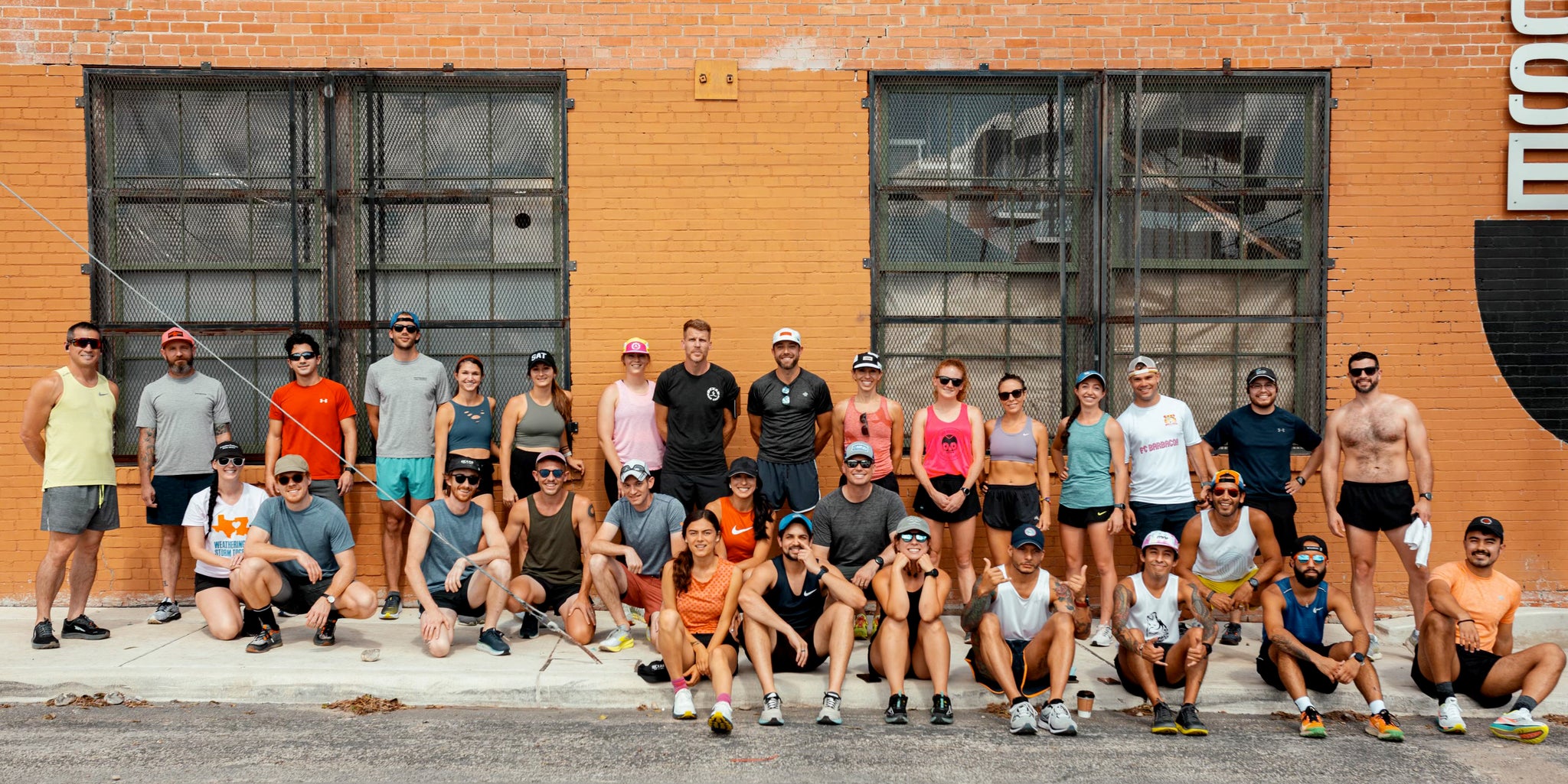 Group of runners stand in front of a brick building after a 3 mile run