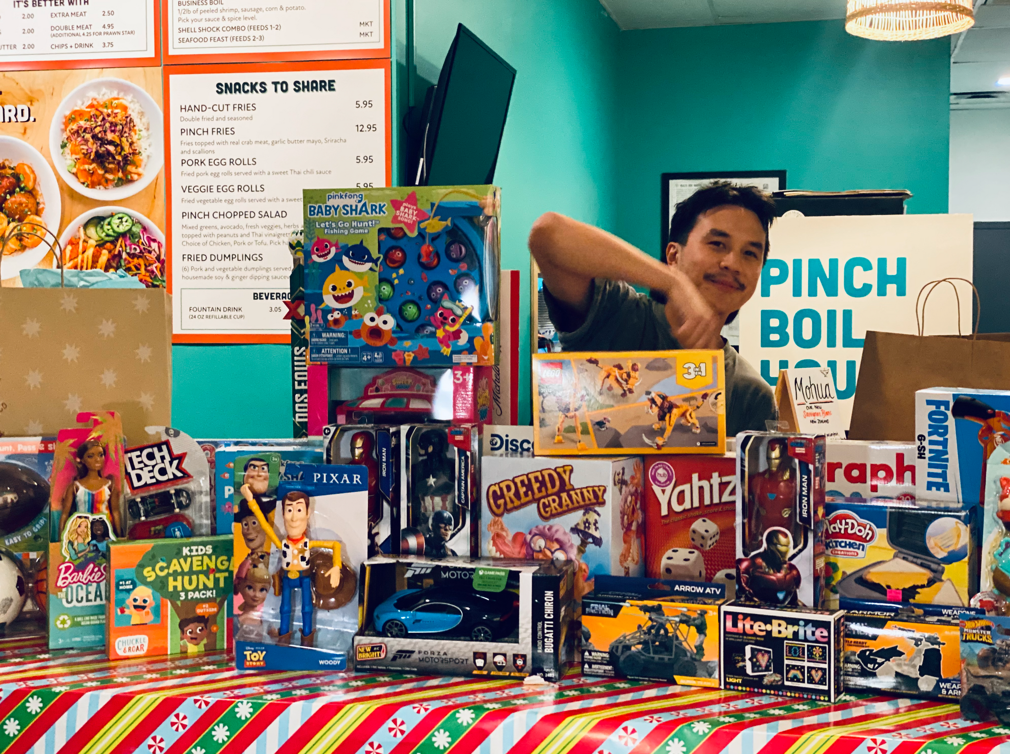 Man stands in front of a table full of toys that have just been donated by guest