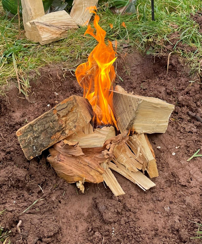 lighting the outdoor fire with flaming firewood