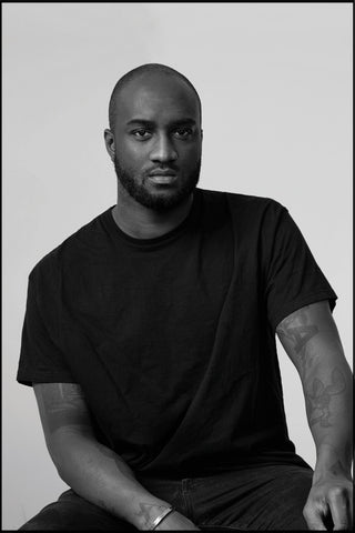 The Fashion Designer Virgil Abloh is Sitting on a chair and wearing a black t-shirt