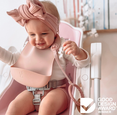 gigi silicone bib one handed, a baby wearing a pink headband sitting in highchair wearing bib