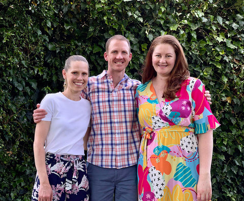 A photo of the Minting Memories team, Kate on the left is wearing a white top, Andrew in the middle is wearing a red and blue check shirt, Jane on the right is wearing a bright colourful dress. They are all standing close together and smiling