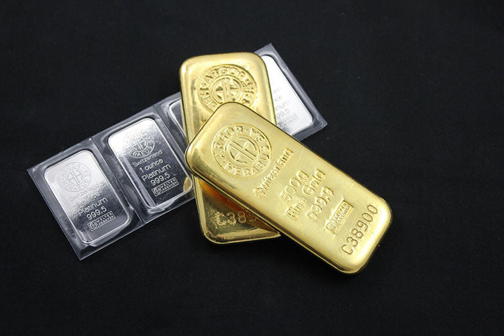 A row of 1 oz silver bars and large gold bullion bars