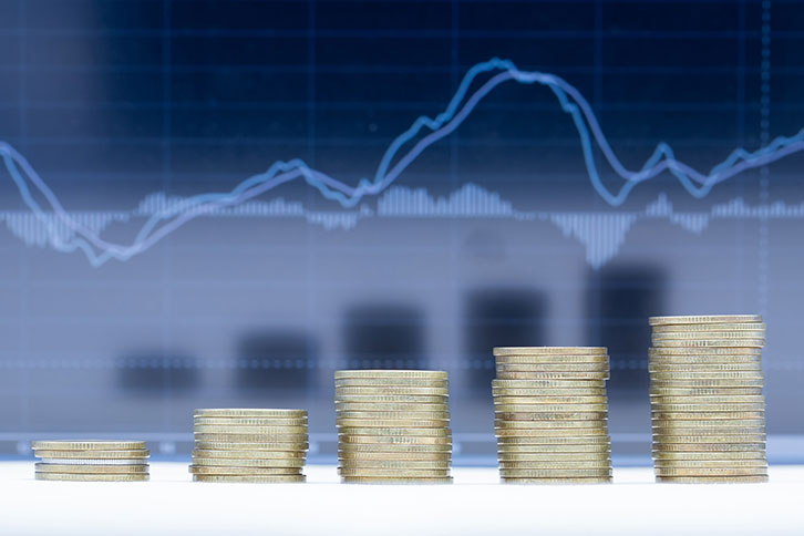 Stack of coins in front of a graph charting capital gains