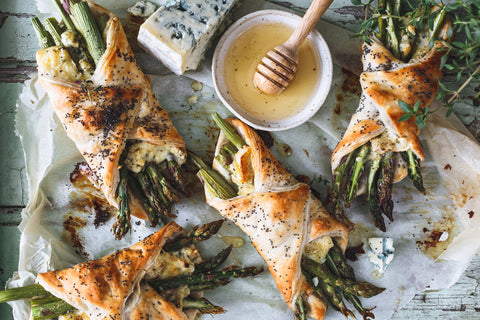 Asparagus wrapped in puff pastry and surrounded by blue cheese