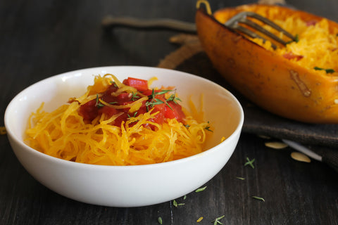 A bowl of spaghetti squash with diced tomato on top.