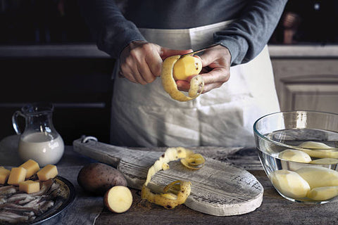 Man cutting potatoes wearing white apron.