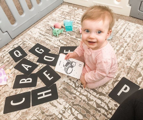 toddler playing with flashcards on play mat