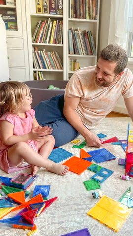 Dad and daughter playing with toys on play mat