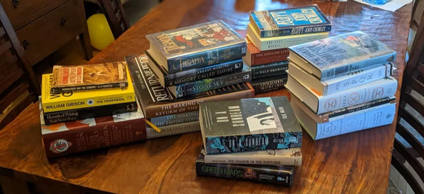 Piles of books on a wooden table.