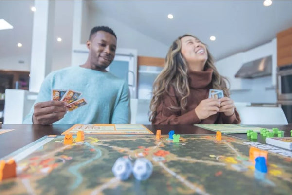 Two people playing Root the board game, laughing