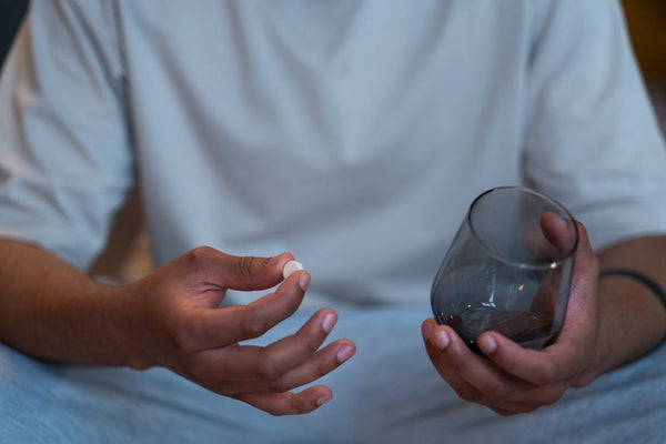 Person taking a melatonin pill and holding a glass