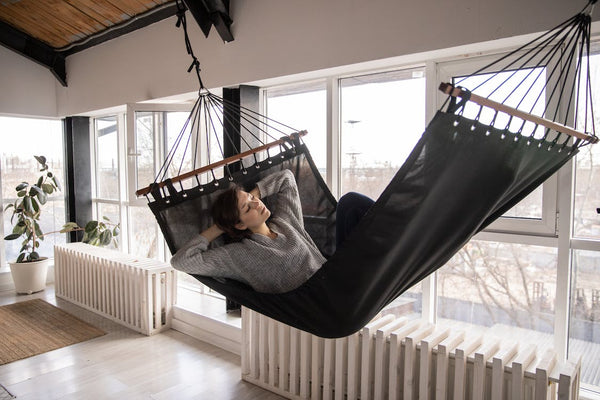 Woman resting in a hammock at home during early afternoon