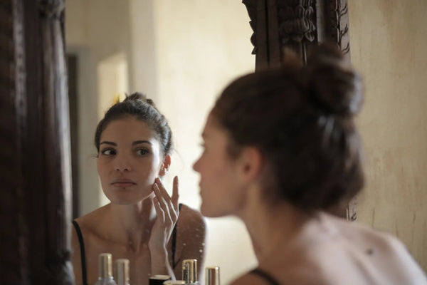 Woman doing her skincare routine in front of a mirror