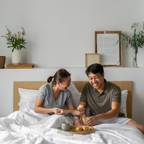 Couple having breakfast on the bed covered in Weavve's cotton bed sheets