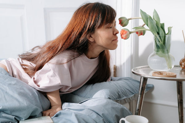 Woman smelling flowers in vase on table