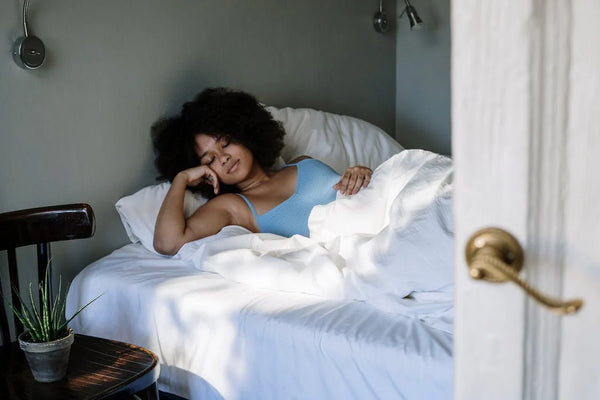 Curly haired woman sleeping on white sheets and pillows
