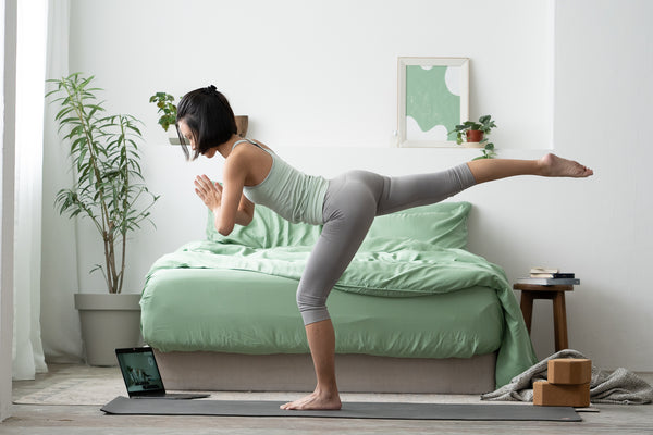 Girl exercising beside green-themed bed