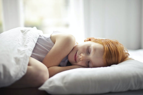 Girl lying on bed with white bed sheets