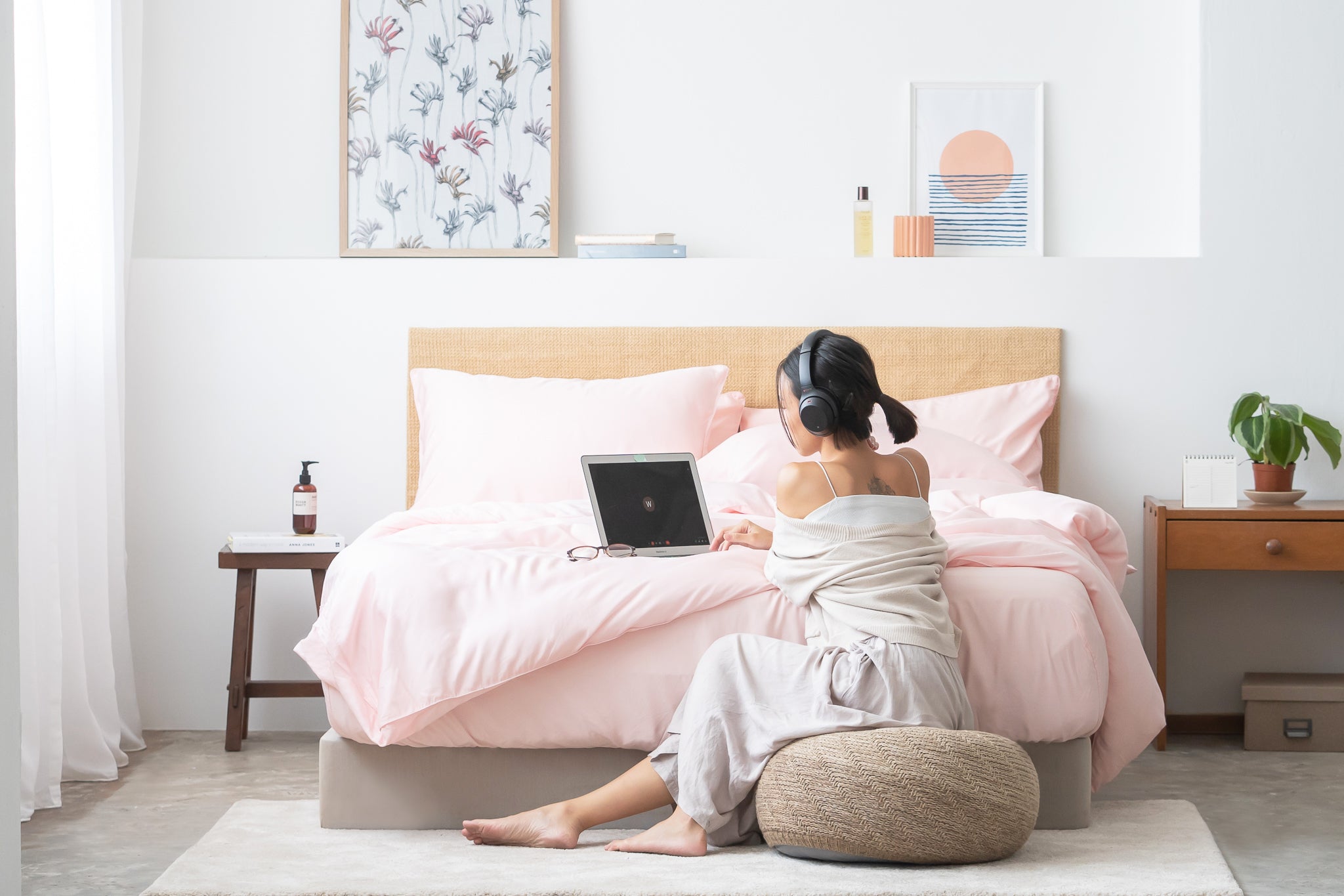 girl using laptop on bed with headphones featuring Weavve's tencel lyocell  fitted sheet set in pink