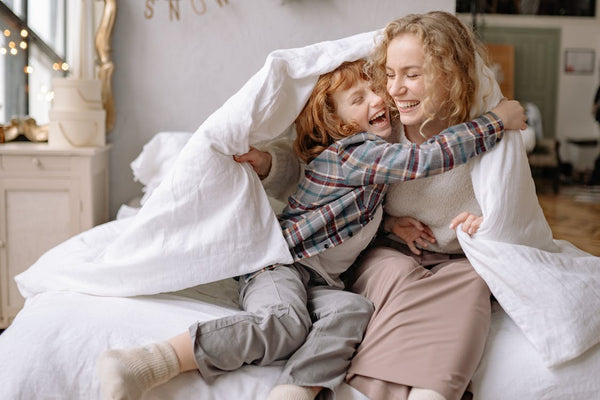 Mother and daughter smiling wide under a blanket with TOG rating
