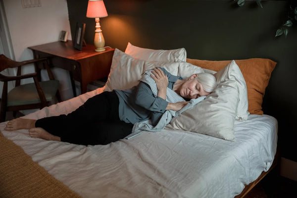 Old woman sleeping on the bed with silk pillows