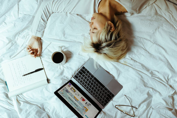 Student sleeping on bed near laptop and cup