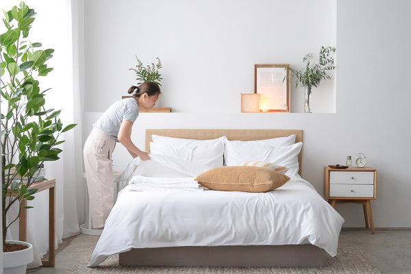Woman fixing white bed sheets