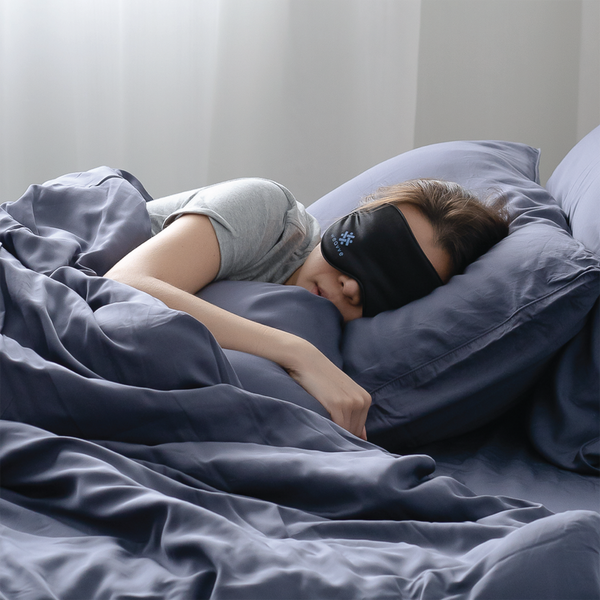 Woman wearing eye mask while sleeping on cooling bed sheets