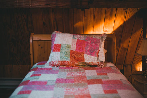 Wooden interior room with a bed covered with quilt