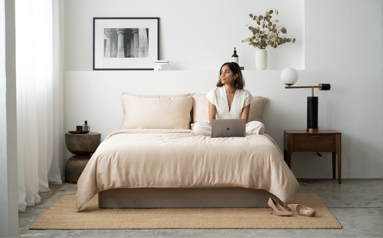 girl sitting on bed with Weavve's light brown bedsheets