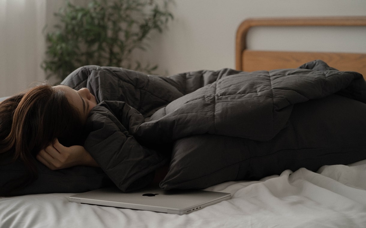 girl snuggling under a weighted blanket