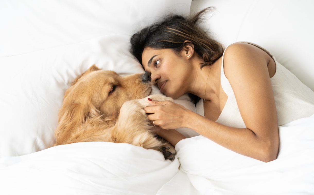 lady and dog on white bed