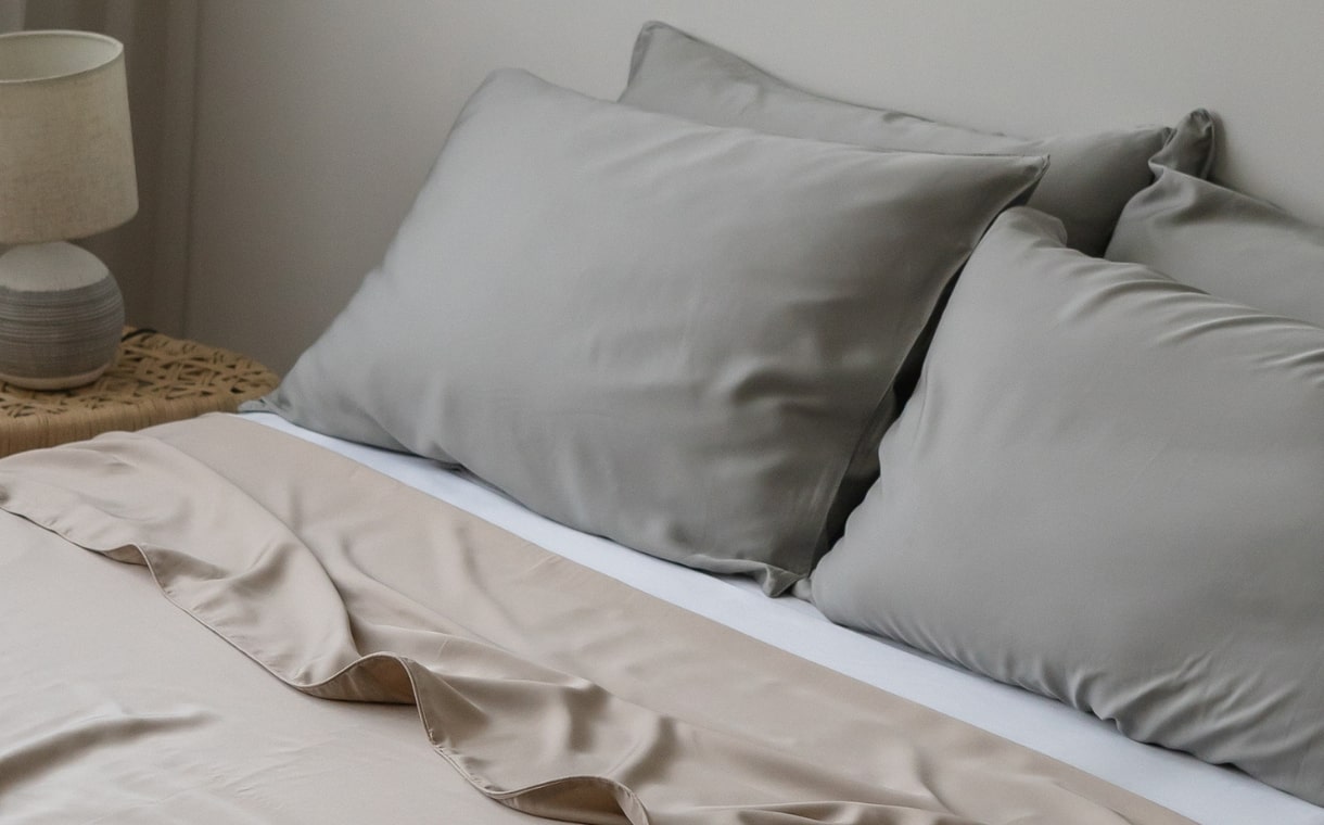 white bed with brown top sheets & grey pillowcases