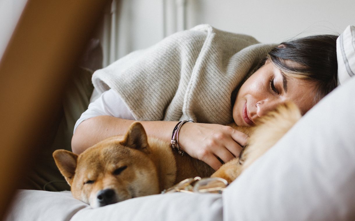 woman and dog sleeping together on bed
