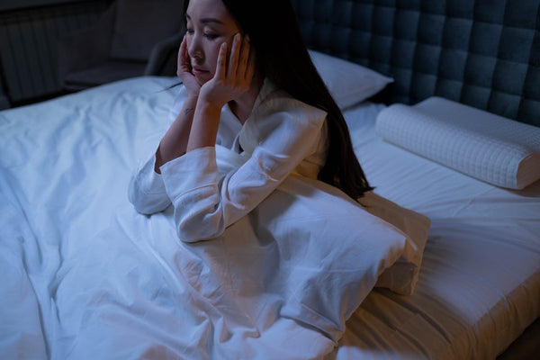 woman in white long sleeves sitting on bed