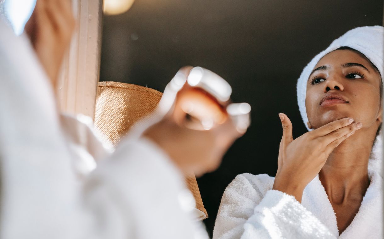 woman looking at the mirror while touching her face