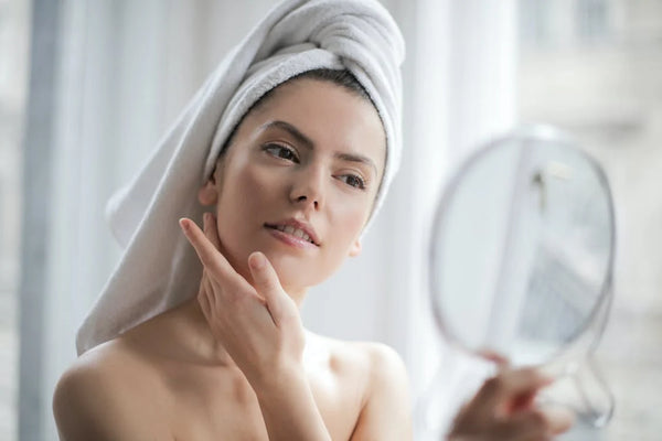 woman looking at the mirror while touching her skin