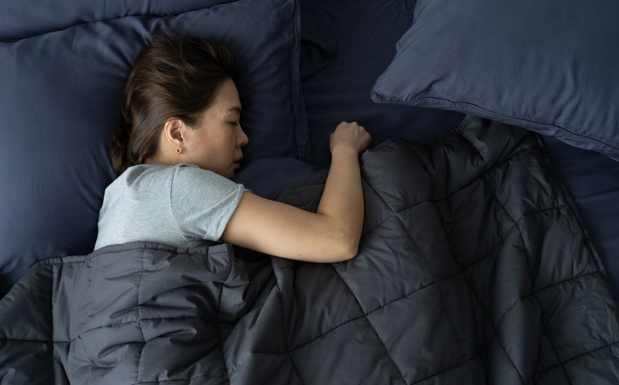 woman sleeping under a weighted blanket