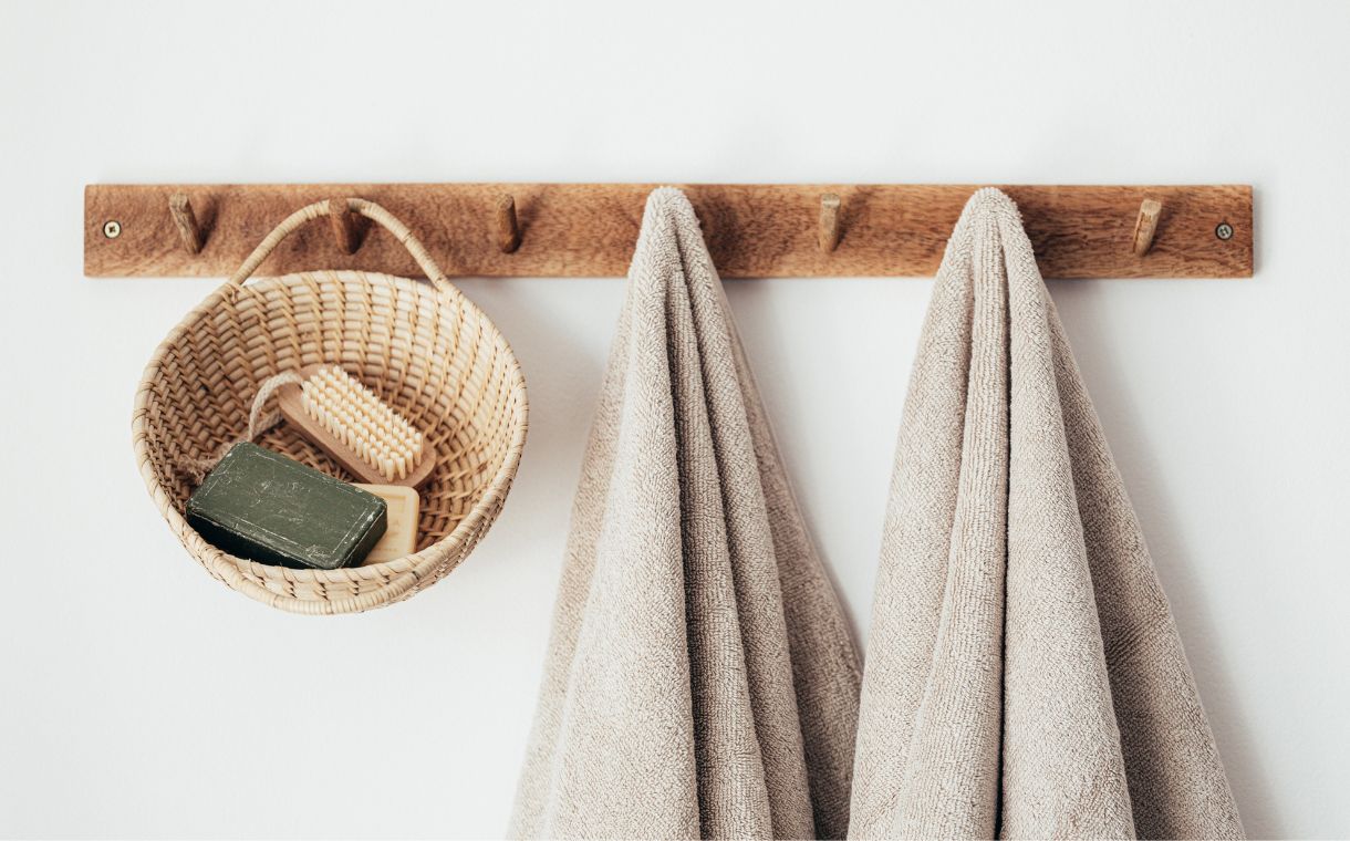 wooden hanger with towels and basket with bathroom products