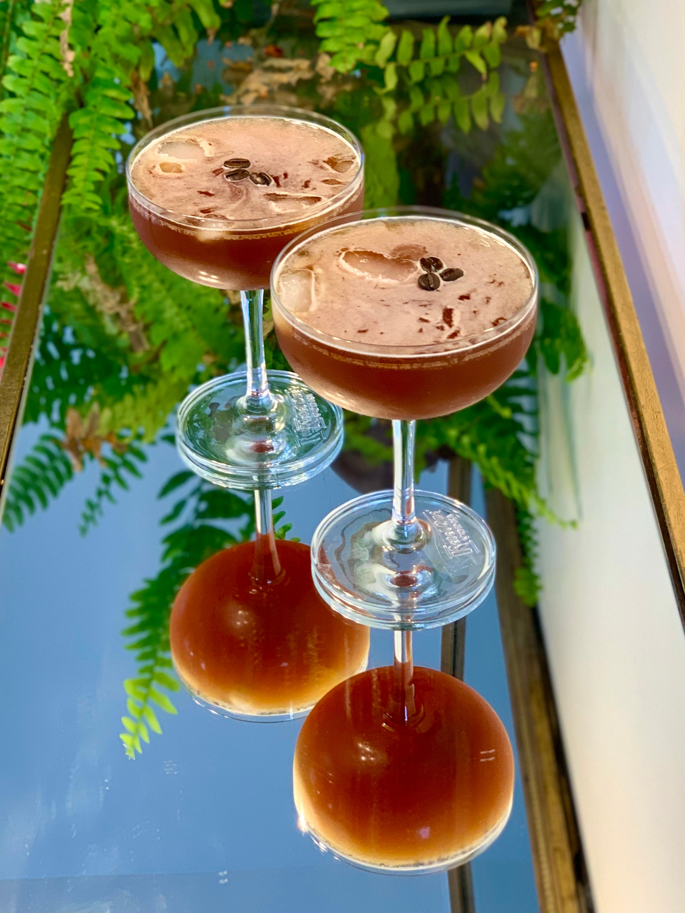 Photo of two espresso cocktails in martini glasses on a mirrored table